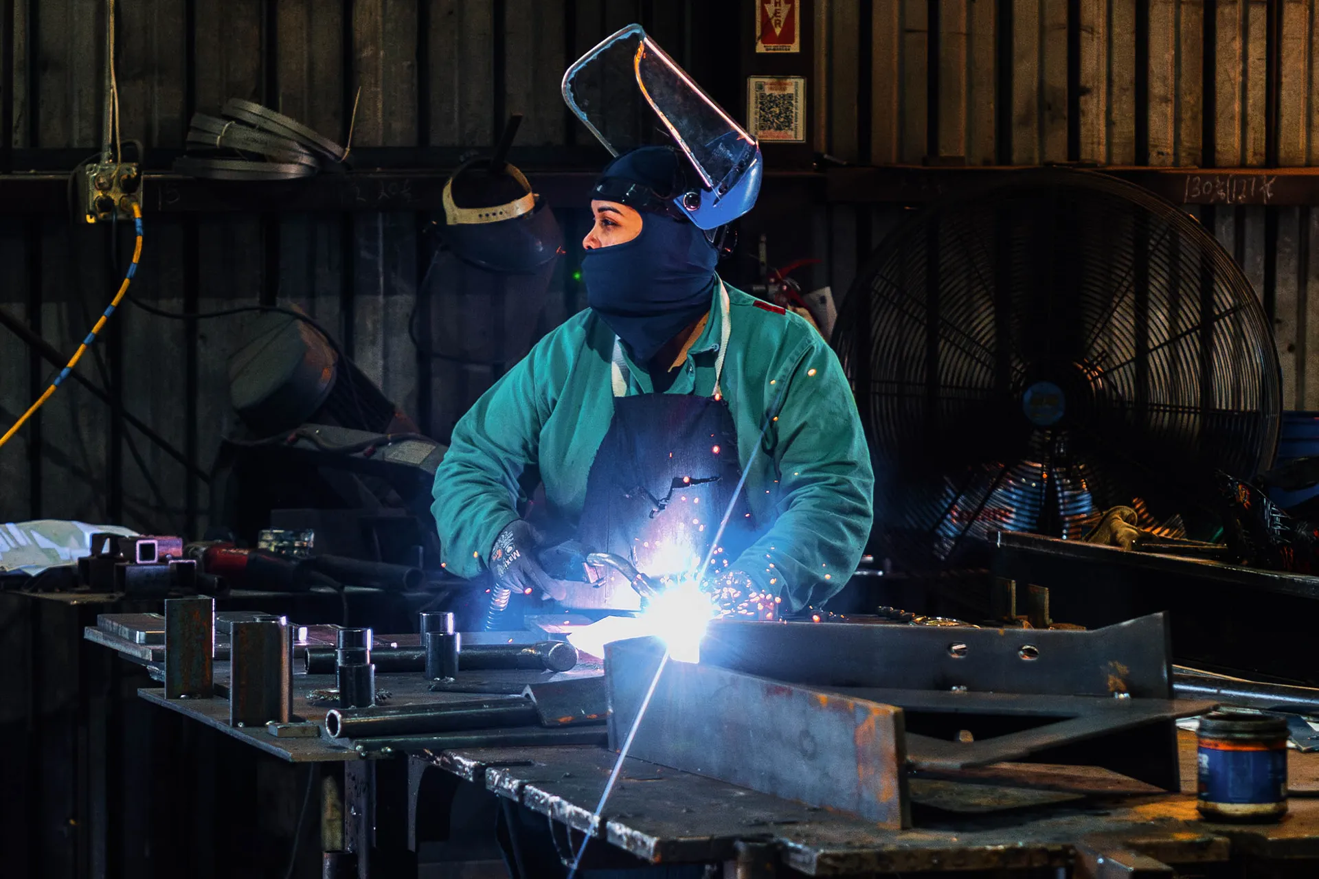 Trailer manufacturing worker welding steel frame components in fabrication shop